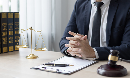 A California worker's compensation lawyer sits at a desk with hands clasped together while reading through a legal document