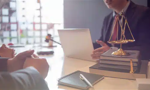 A California car accident lawyer is speaking to a client about the details of a file on an open laptop