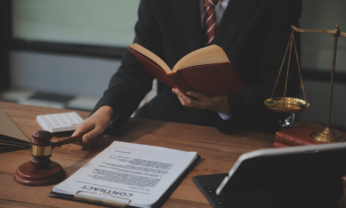 A California persoanl injury lawyer reading a law book while holding a hammer in their right hand