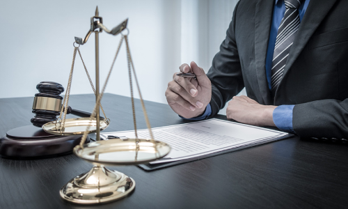 A personal injury lawyer serving California reads a contract before signing it while he sits in a law office