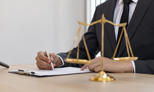 A California personal injury lawyer signing a legal document while sitting in a law office