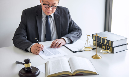 A California slip and fall lawyer takes notes on a document while sitting at an office desk with an open law book