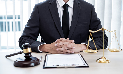 A California worker's compensation lawyer sitting upright with hands clasped togehter while reading a legal document on the table