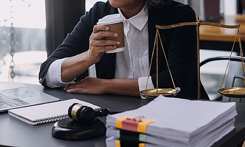 A California car accident lawyer holding up a cup of coffee and reading files on a laptop