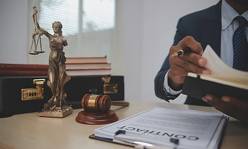 A personal injury lawyer reading a law book and sitting at an office desk with a contract laid out