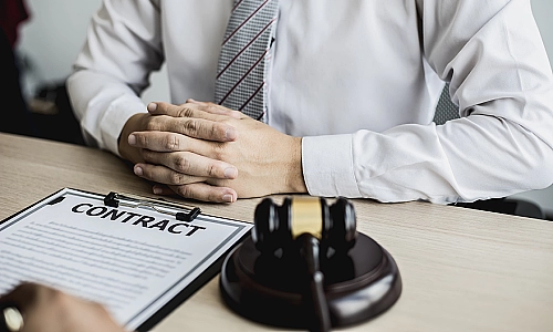 A workplace injury lawyer sitting at an office desk while looking over a contract facing an out of view client